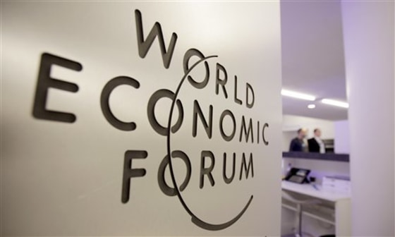 People walk by a sign in the meeting center at the World Economic Forum in Davos, Switzerland.